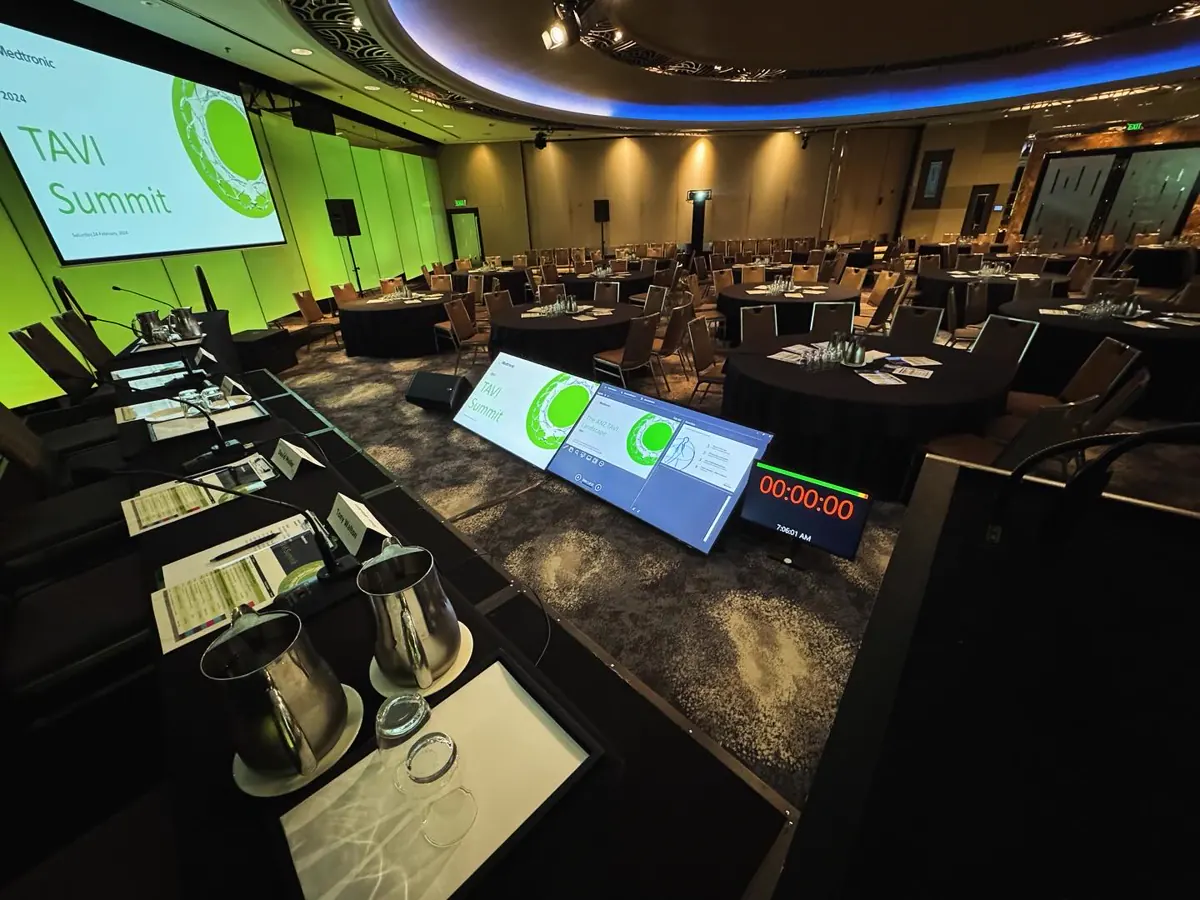 A full conference room set with staging, screens and table audio